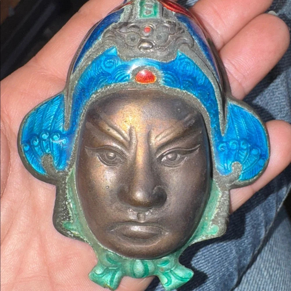 Vintage enameled metal decorative mask of an Asian man's face.